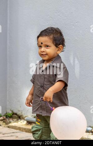 Galle, Sri Lanka - 06 08 2020: 1-year-old kid with his balloon playing outside of the home. Stock Photo