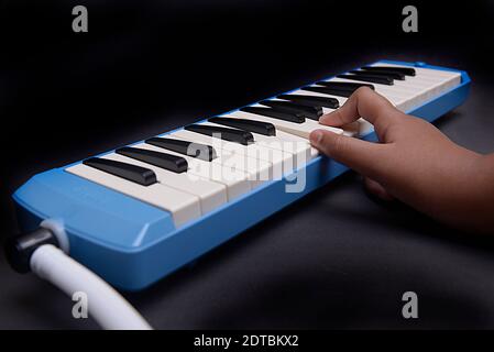 Hand playing pianica blow-organ musical instrument with black background Stock Photo