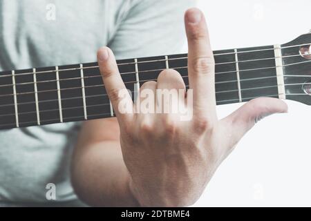 Close-up of man showing horn sign on guitar fretboard Stock Photo