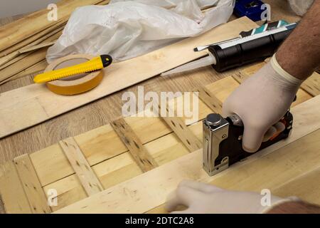 Man fastens boards with a stapler Stock Photo