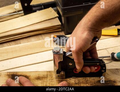 Man fastens boards with a stapler Stock Photo