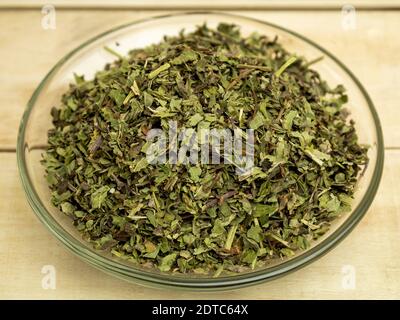Oregano seasoning in a glass plate on a wooden background Stock Photo