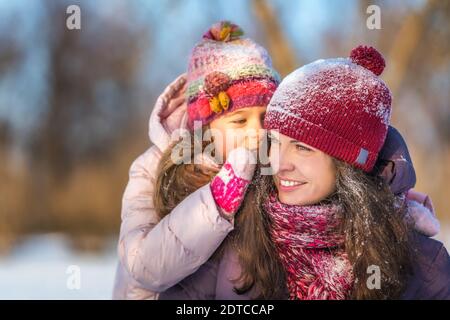 Little girl and her mother playing outdoors at sunny winter day. Active winter holydays concept. Stock Photo