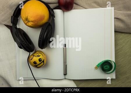 Notebook and pen with headphones top view. Meter and fruits. Frame, blank for recording. Stock Photo