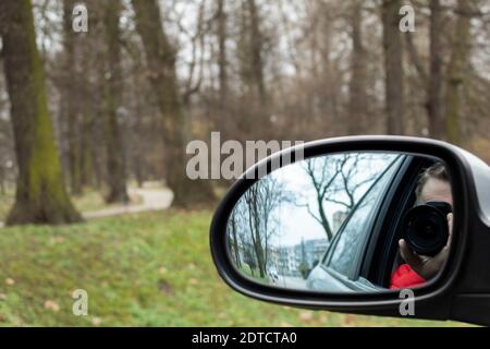 Tracking a private detective hidden photography with a car. Reflection in the mirror of a car with a camera. Paparazzi and shadowing concept Stock Photo