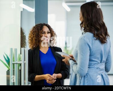 Smiling businesswomen talking in office Stock Photo
