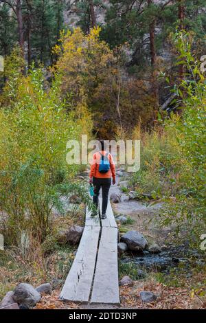 WOMAN HIKING OVER STREAM IN BANDELIER NATIONAL MONUMENT, NM, USA Stock Photo