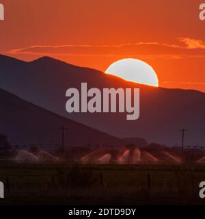 USA, Idaho, Bellevue, Irrigation equipment in field and sun setting behind mountain Stock Photo