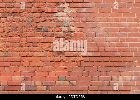 Red brick wall made of clay stones. Texture of red bricks that crumble Stock Photo