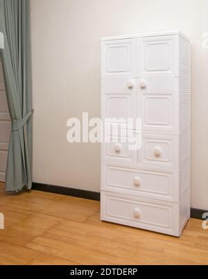 White plastic wardrobe with drawers on wooden floor in bedroom Stock Photo