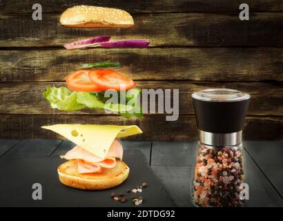 A hamburger hovering in the air with a shred and cheese. The sandwich is frozen. Ham and cheese sandwich Stock Photo