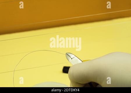Biting the wire with wire cutters. Cut the steel thread with side cutters. Metal tongs and steel string. Stock Photo