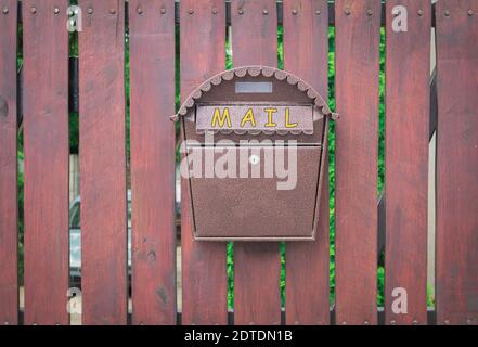 A mail box hangs on a fence. Mailbox on a wooden fence Stock Photo