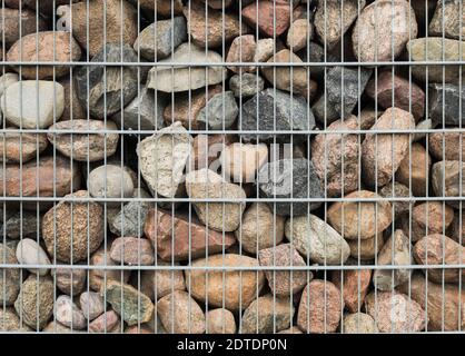 Background of large stones in the grid. The texture of the stone wall is covered with a metal mesh Stock Photo
