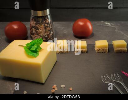 Canapes with cheese and vegetables. Ingredients for sandwiches, cheese and vegetables with spices. The process of making canapes. Diced Cheese, Camemb Stock Photo