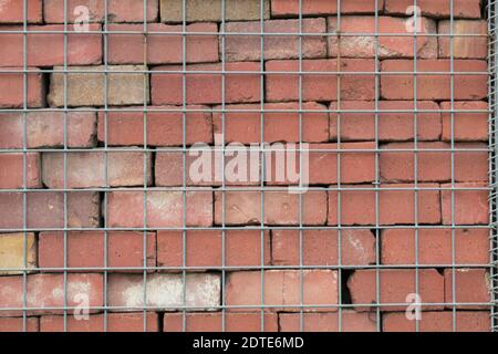 Red stone and metal mesh. Background red stone wall supported by metal mesh. Not an ordinary wall of stone Stock Photo