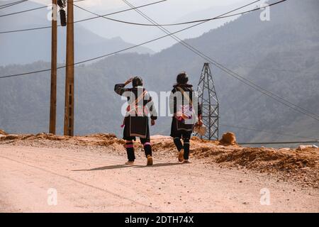 Women from the Hmong tribe wearing their traditional clothes while walking back to Lao Cai Village in Sa pa, Vietnam Stock Photo