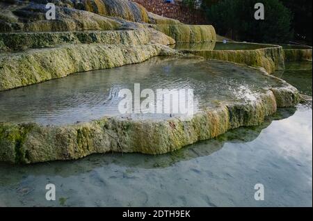 Red travertine terraces in Karahayit. Clear thermal water baths. Limestone formation with hot water. Pamukkale / Denizli, Turkey. Stock Photo