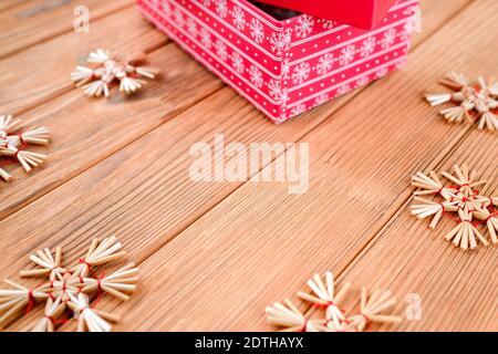 New Year card on a wooden background. Red box. Straw toy snowflakes. Stock Photo