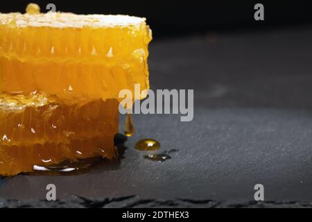 fresh golden honey dripping from pieces of cut honeycomb Stock Photo