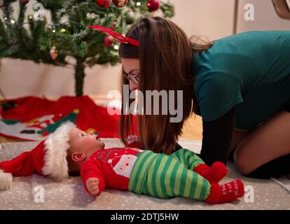 Mother playing with lovely baby near Christmas tree Stock Photo