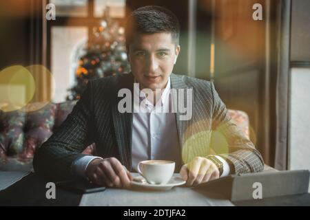 A young and attractive man uses his tablet while drinking coffe in an indoor restaurant Stock Photo