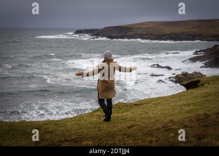 The woman enjoying view of Atlantic ocean storm on the shore of Malin Beg, small Gaeltacht village south of Glencolumbkille, County Donegal, Ireland Stock Photo