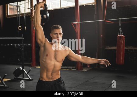 Young handsome sportsman doing exercises with a kattlebell in the gym Stock Photo