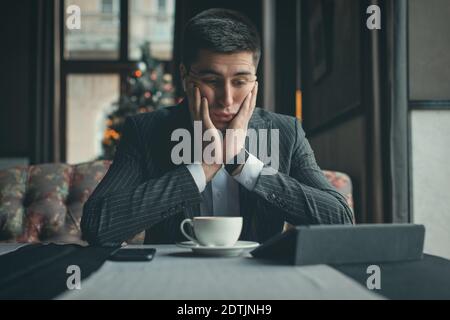 A young and attractive man uses his tablet while drinking coffe in an indoor restaurant Stock Photo