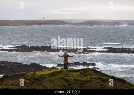 A woman enjoys a view of the Atlantic storm on the shore of Malin Beg, in the small village of Gaeltacht,south of Glencolumbkille, Co.Donegal, Ireland Stock Photo