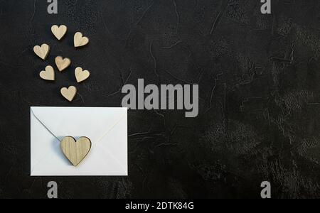 Valentine's day romantic concept. Wooden hearts and envelop on black background.  Stock Photo