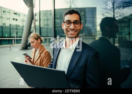Smiling mixed race businessman standing with female colleague busy researching working outside  Stock Photo