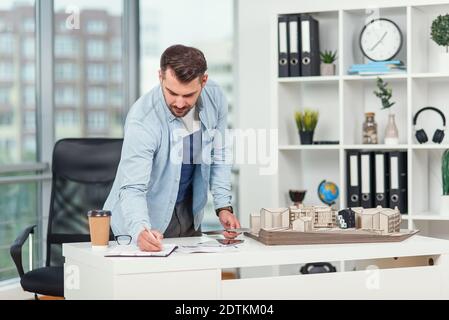 Handsome senior architect working on a construction project, he examines the model on which he works Stock Photo