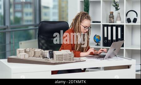 Handsome senior architect working on a construction project, he examines the model on which he works Stock Photo