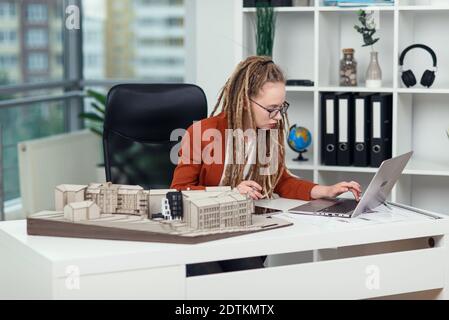 Handsome senior architect working on a construction project, he examines the model on which he works Stock Photo
