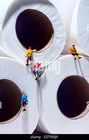 Conceptual image of miniature figure people climbing up toilet tissue rolls