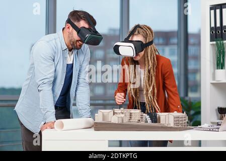 Professional architect working at office desk and wearing a VR headset, he is viewing a virtual reality interface Stock Photo
