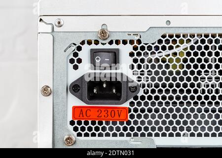 Rear view of tower computer case with new power supply unit installed. On Off switch, power cord socket and voltage sticker on personal computer PSU. Stock Photo