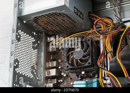 Inside of tower computer case with dusty faulty power supply unit before replacement with a new one. Personal computer PSU replacement, hardware. Stock Photo