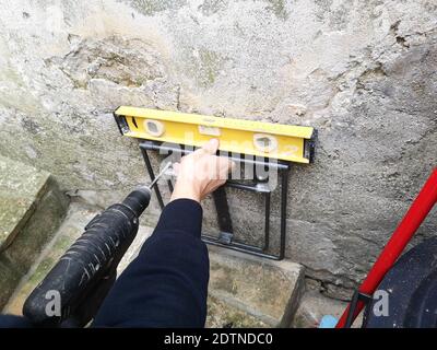 A carpenter using a level tool and a drill tool while working Stock Photo