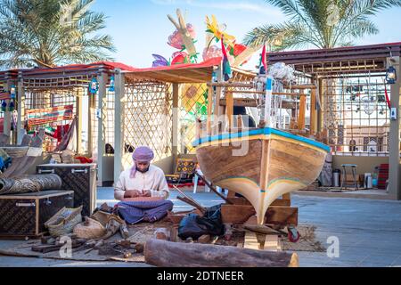 Arabic fisherman, repairing home-made fishing net and wooden yacht, wearing face mask and sits on the floor of traditional boam Stock Photo