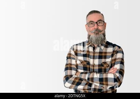 man with a wide beard, glasses and checkered shirt, standing with arms crossed and staring with a serious face. concept people with different looks Stock Photo