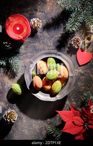 Walnut shaped cookies with Dulce De Leche or condensed milk in vintage tin bowl. Dark textured background with winter decorations Fir twigs Stock Photo