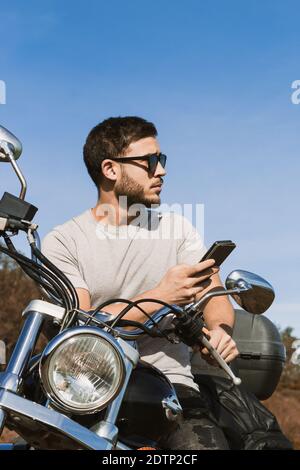 Biker sitting on the motorcycle taking a picture of the landscape with the mobile Stock Photo