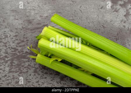 Close view of several stalks of fresh organic celery on a gray mottled background. Stock Photo
