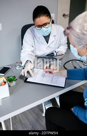 Female doctor explaining to her patient the consent form to coronavirus vaccine Stock Photo