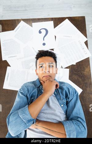 top view of pensive african american man looking at camera near documents with contract lettering on desk Stock Photo