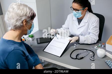 Female doctor explaining to her patient the consent form to coronavirus vaccine Stock Photo