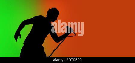 Flyer. Silhouette of young male guitarist isolated on green-orange gradient studio background in neon. Beautiful shadow in action, performing. Concept of human emotions, expression, ad, music, art. Stock Photo