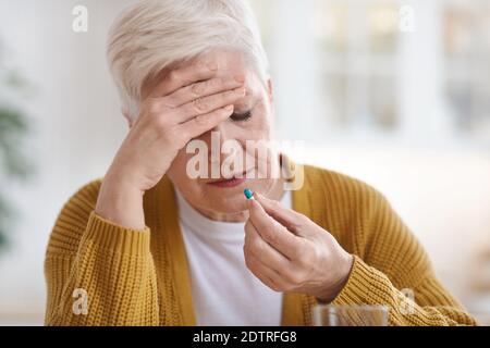 Senior woman suffering from headache, taking pill Stock Photo